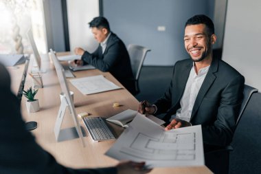 Gülümseyen Afrikalı iş adamı, iş yerinde otururken meslektaşından belgeler alıyor.