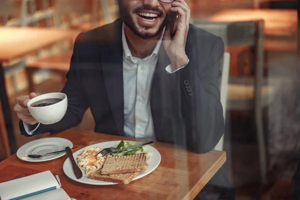 Indian businessman is talking phone with client during lunch time in cozy cafe. High quality photo