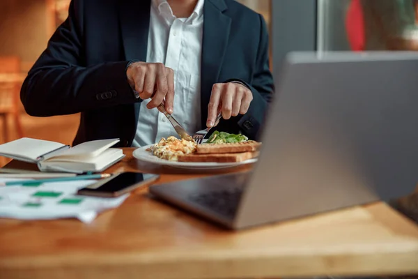Close up of businessman eating lunch during break after work in cafe. High quality photo