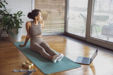 Evde dizüstü bilgisayar kullanarak esneme egzersizi yapan bir kadın. Yüksek kalite fotoğraf