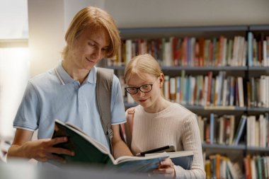 Two friends student chooses books while standing in the university library . Blurred background