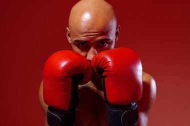 Man wearing boxing gloves practicing for fight on studio background with color filter