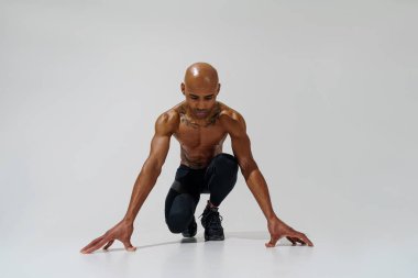 Çıplak gövdeli sporcu beyaz stüdyo arka planında ısınıyor. 