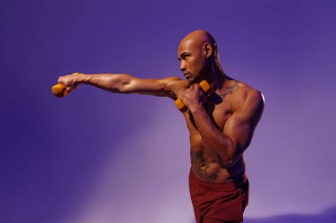 Muscular man doing exercise with weight dumbbells on studio background with color filter
