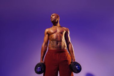 Muscular man doing exercise with weight dumbbells on studio background with color filter