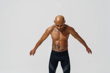 Çıplak gövdeli sporcu beyaz stüdyo arka planında ısınıyor. 