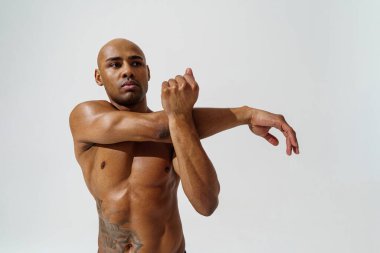 Çıplak gövdeli sporcu beyaz stüdyo arka planında ısınıyor. 