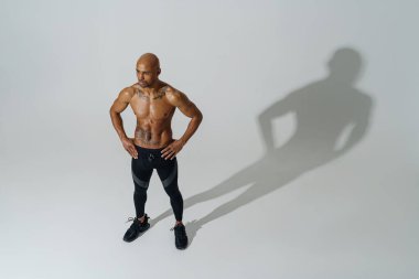 Çıplak gövdeli sporcu beyaz stüdyo arka planında ısınıyor. 