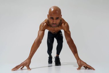 Çıplak gövdeli sporcu beyaz stüdyo arka planında ısınıyor. 