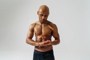 Çıplak gövdeli sporcu beyaz stüdyo arka planında ısınıyor. 
