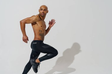 Profesyonel atlet beyaz stüdyo arka planında gölgeli bir şekilde koşuyor.