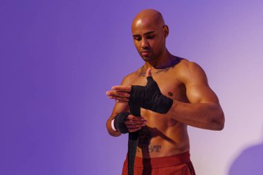 Sporty man taping his arms with bandage before fight on studio background. High quality photo