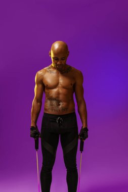 Man performs exercises with expander on studio background with color filter. Strength and motivation