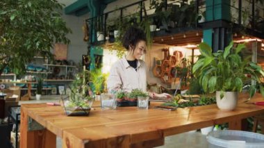 Florist woman works in her small floral business surf for information about plants about the climate