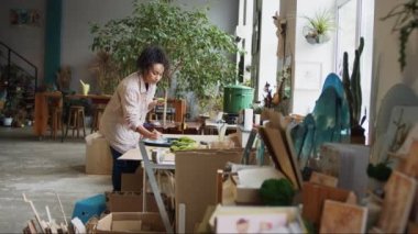 Woman decorator making green ikebana on tray in florist studio. High quality photo