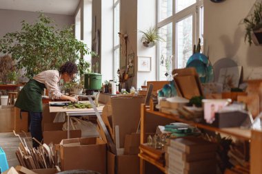 Woman decorator making green ikebana on tray in florist studio. High quality photo