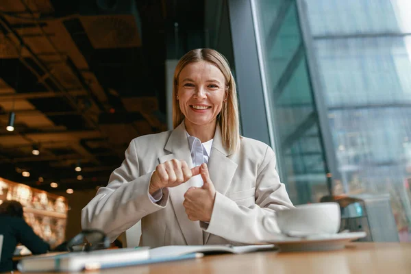 Businesswoman communicating in sign language while looking at camera . High quality photo