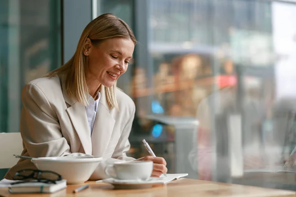 Wanita Pebisnis Tersenyum Makan Siang Dan Membuat Catatan Saat Bekerja — Stok Foto
