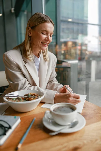 Wanita Pebisnis Tersenyum Makan Siang Dan Membuat Catatan Saat Bekerja — Stok Foto