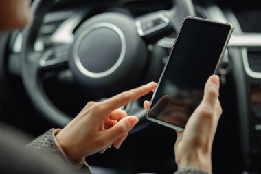 Kadın sürücü elleri, kendi arabasında direksiyon başında otururken telefon kullanıyor. Yüksek kalite fotoğraf