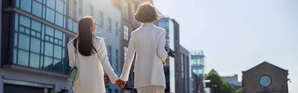 stock image Women in trendy outfits laugh and walk outside near business center. Blurred background