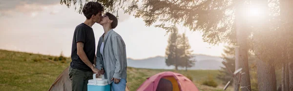 Male Tourist Kissing Girlfriend Holding Portative Fridge Camping Site Rural — Stockfoto