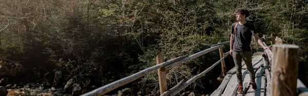 Genç Bir Gezgin Tahta Köprüde Duruyor Ormandaki Hızlı Dağlara Bakıyor — Stok fotoğraf