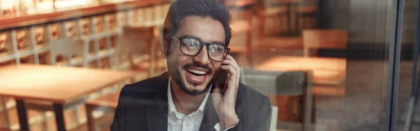 stock image Indian businessman is talking phone with client during lunch time in cozy cafe. High quality photo