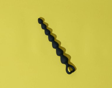 Anal plug or dildo on yellow background with shadows. Sex toys for anal play. High quality photo