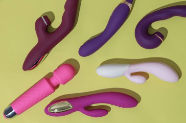 Many dildo vibrators on yellow background with shadows. Sex toy for adult. High quality photo