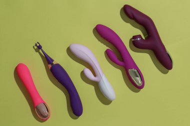 Many dildo vibrators on yellow background with shadows. Sex toy for adult. High quality photo