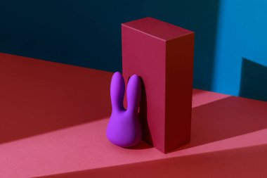 Violet dildo vibrator for clitoris with pink gift box on colored background. High quality photo