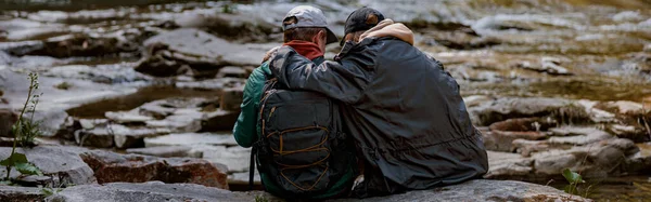 Back View Couple Hikers Sitting Bank Rocky River Hugging Hiking — Foto de Stock