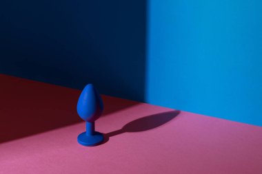 Blue butt plug or buttplug sex toy on a colorful background. Anal toy on contrast shadows background