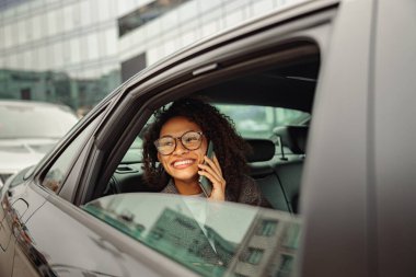 Arabada arka koltukta otururken müşteriyle telefonda konuşan çekici bir iş kadını.
