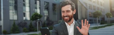 Businessman during break make videocall to friend on background of office building