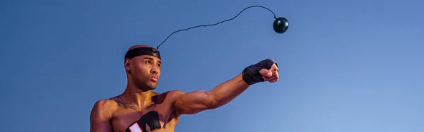 裸の胴を持つ男は カラーフィルターとスタジオの背景にトレーニングのためのボクシングボールシミュレータを使用しています — ストック写真