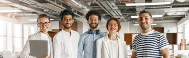 Happy group of businesspeople laughing cheerfully in a modern workplace. Blurred background