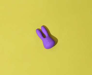Violet dildo vibrator for clitoris on yellow background with contrast shadows. High quality photo