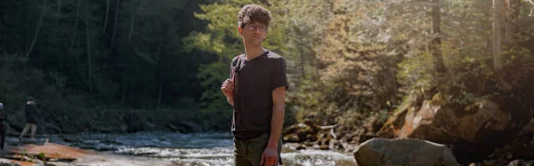 Dağlarda Nehirde Kayaların Üzerinde Duran Sırt Çantalı Genç Bir Gezgin — Stok fotoğraf