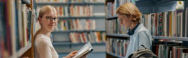 Friends student sit on floor near bookshelves in library and studying. Education concept