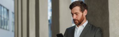 Businessman in suit with phone drinking coffee near office building. Business concept