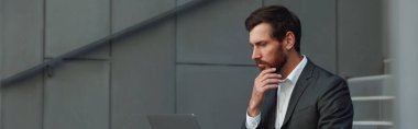 Businessman in suit working laptop near office building. Business concept