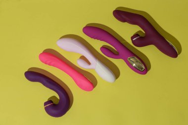 Many dildo vibrators on yellow background with shadows. Sex toy for adult. High quality photo