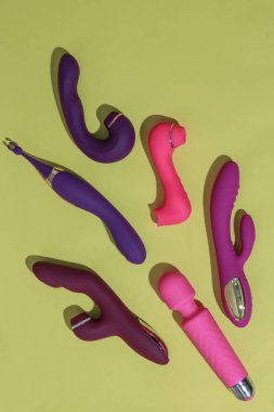 Many dildo vibrators on yellow background with shadows. Sex toy for adult. High quality photo