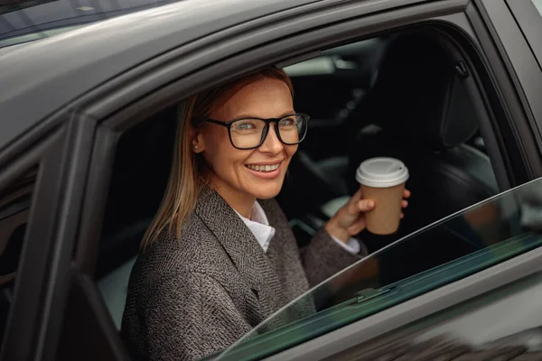 Uśmiechnięta Kobieta Pasażer Pije Kawę Wynos Patrząc Przez Okno Taksówki — Zdjęcie stockowe