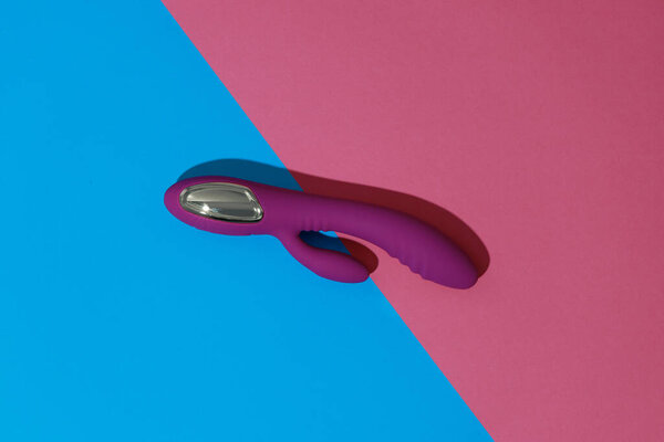 Violet dildo vibrator on colored background with shadows. Sex toy for adult. High quality photo