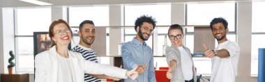 Happy group of businesspeople laughing cheerfully and showing thumbs up in a modern workplace