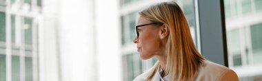 Businesswoman in glasses drinking coffee and making notes while working in cafe. High quality photo