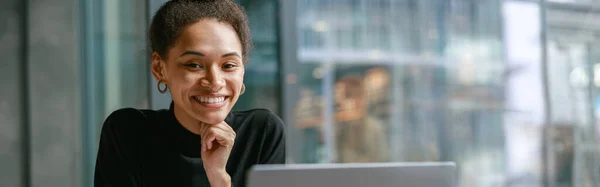 stock image Smiling female student studying on laptop while sitting in cafe. Online education concept